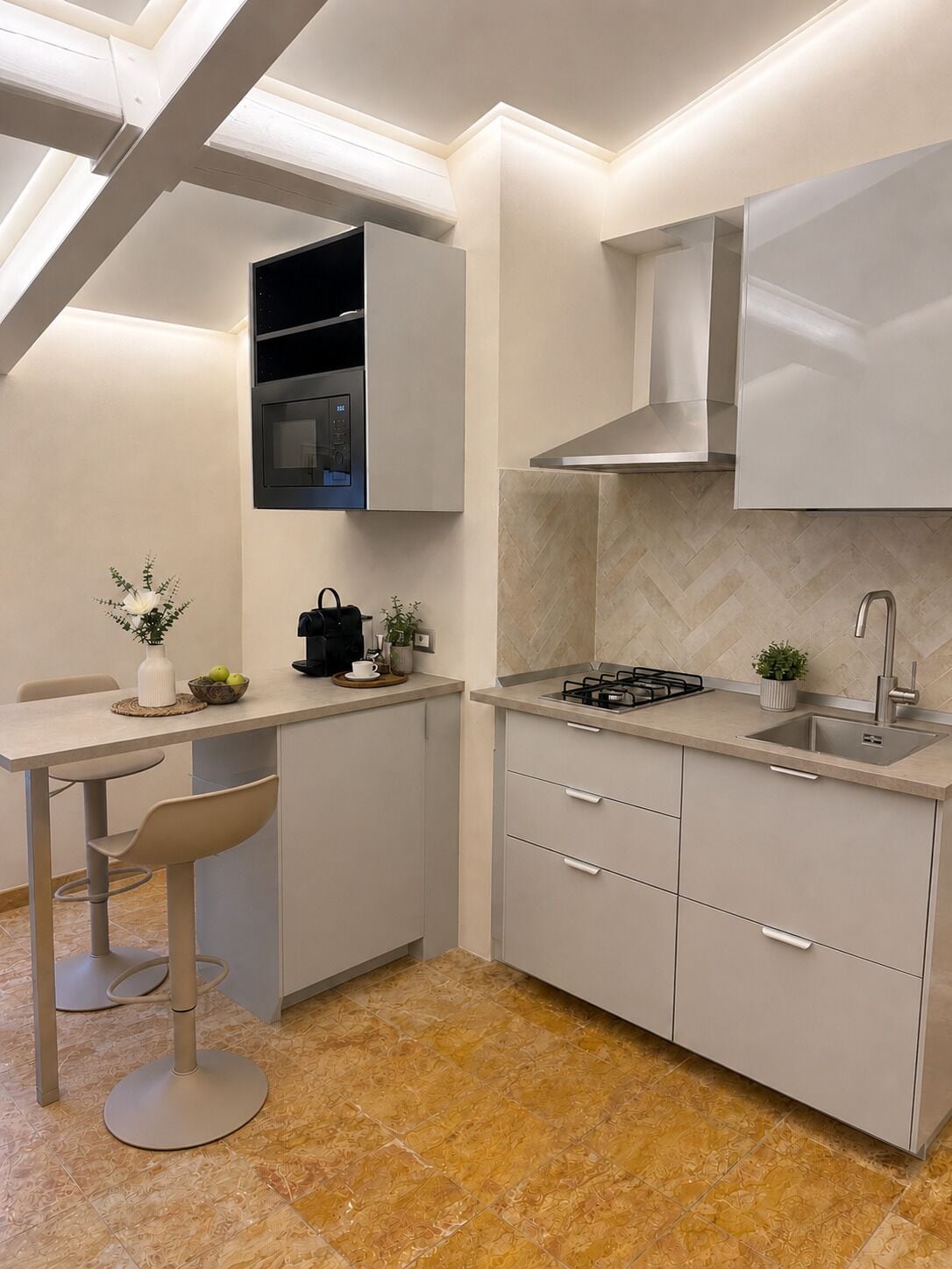 A modern kitchen with a built-in oven, a gas stove, and a sink. There is a dining area with a table and chairs.
