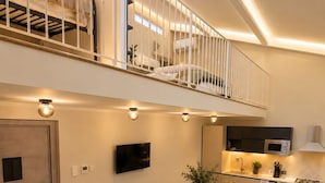 Un apartamento moderno con comedor, cocina y un balcón con cama.