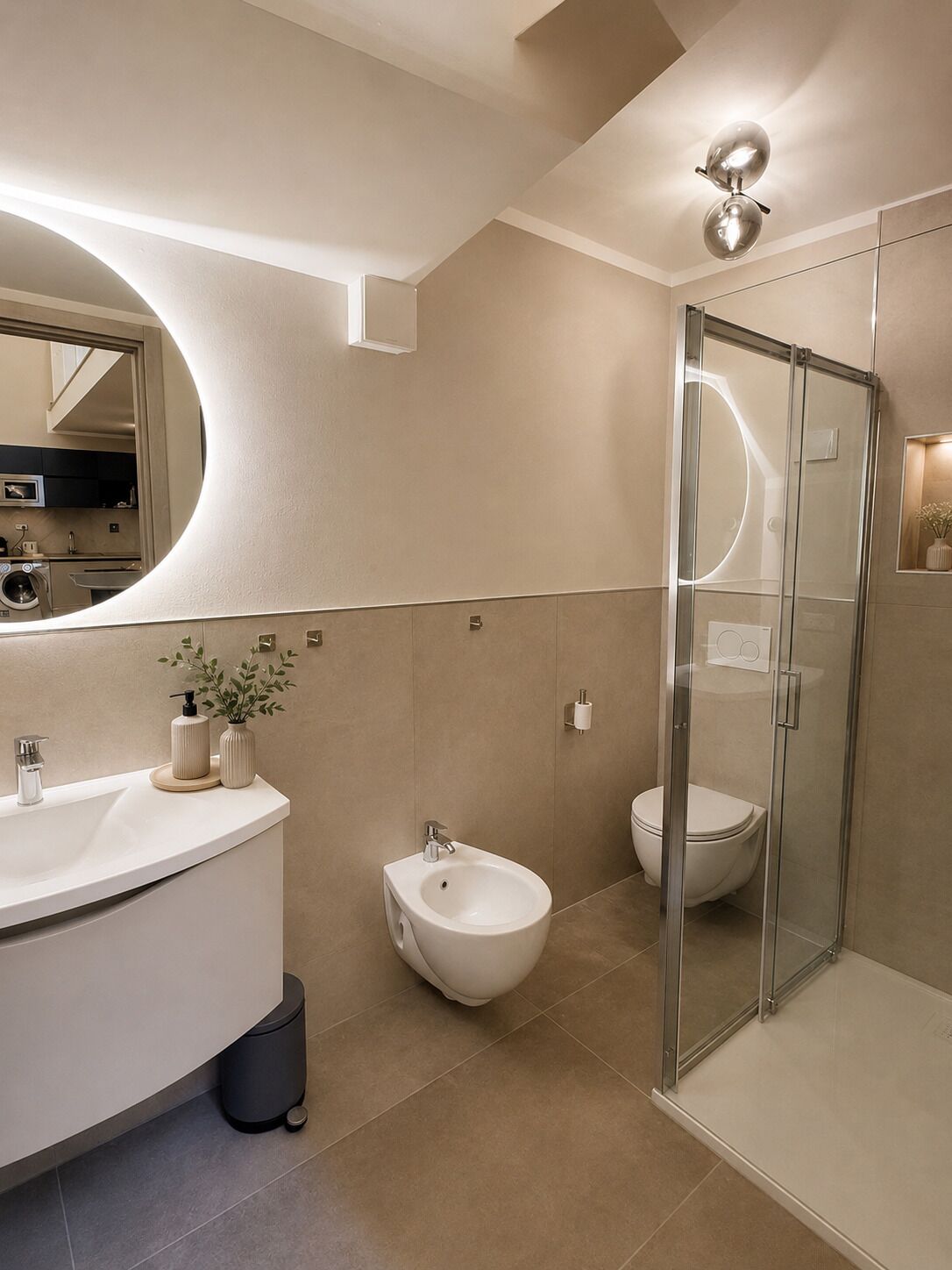 Un baño moderno con un tocador curvo, un bidé, un inodoro y una ducha con cerramiento de vidrio.
