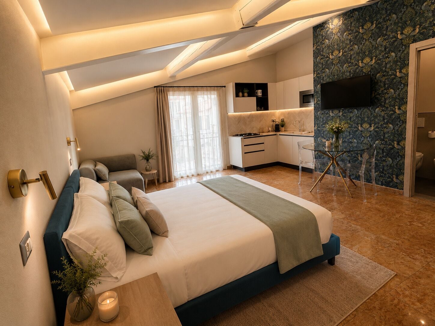 A modern bedroom with a large bed, a sitting area, and a kitchenette.