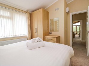 Ein Hotelzimmer mit Bett, einem Holzschrank, einem Nachttisch, einem Spiegel und Blick auf einen Balkon.
