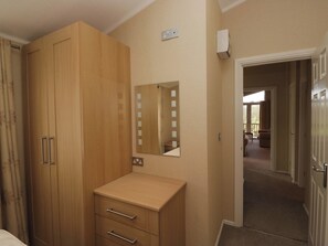 Ein Schlafzimmer mit Holzschrank, einem kleinen Nachttisch, einem Spiegel und einer Tür, die auf einen Balkon führt.