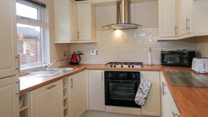 A kitchen with white cabinets, a stove, a microwave, and a toaster. - Wally's Folly (Windermere)