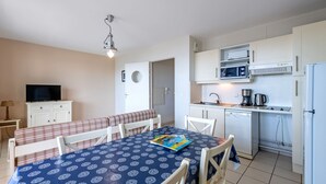 Un espacio habitable compacto con comedor, kitchenette y televisor.
