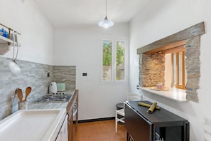 A compact kitchen with a gas stove, a white sink, and a stone accent wall.