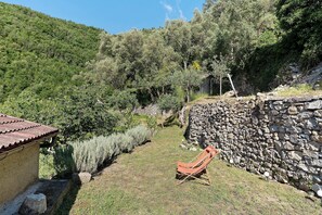 A stone wall, a chair, and a building with a tiled roof.