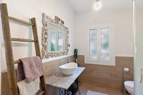 A bathroom with a wooden ladder, a white sink, and a mirror with a decorative frame.