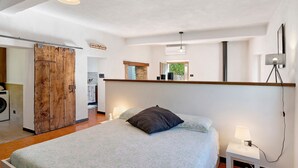 A bedroom with a bed, bedside lamp, and a wooden door.