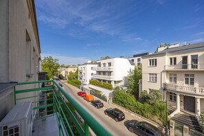 Une rue résidentielle bordée d’immeubles modernes, avec un escalier en métal vert et des voitures garées.