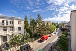 Une rue résidentielle bordée d’immeubles à plusieurs étages, de voitures garées et d’arbres.