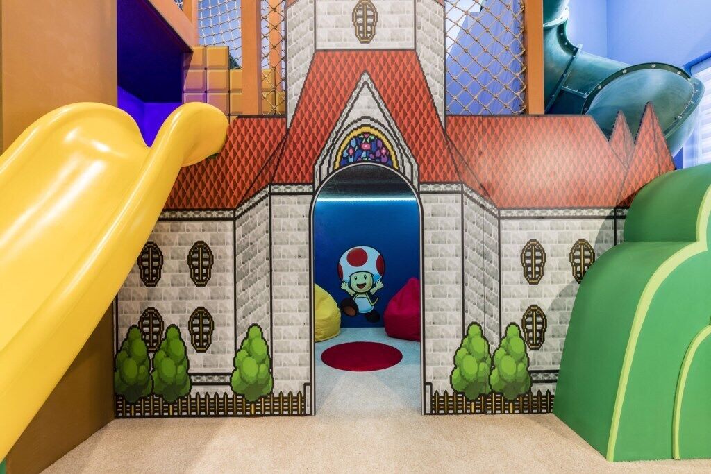 A play area with a slide, a castle-like structure, and a character in a mushroom hat.