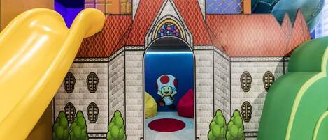 A play area with a slide, a castle-like structure, and a character in a mushroom hat.