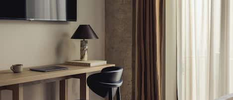 A modern room with a wooden desk, a black chair, a lamp, a laptop, and a book titled 'THE ART OF KINFKOLK.'