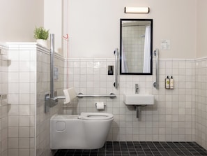 A compact bathroom with a toilet, sink, and mirror. - Native Fulham Broadway (London)