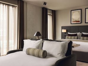 A hotel room with a bed, a bedside table with a lamp, a large mirror, and a framed picture on the wall. - Native Fulham Broadway (London)