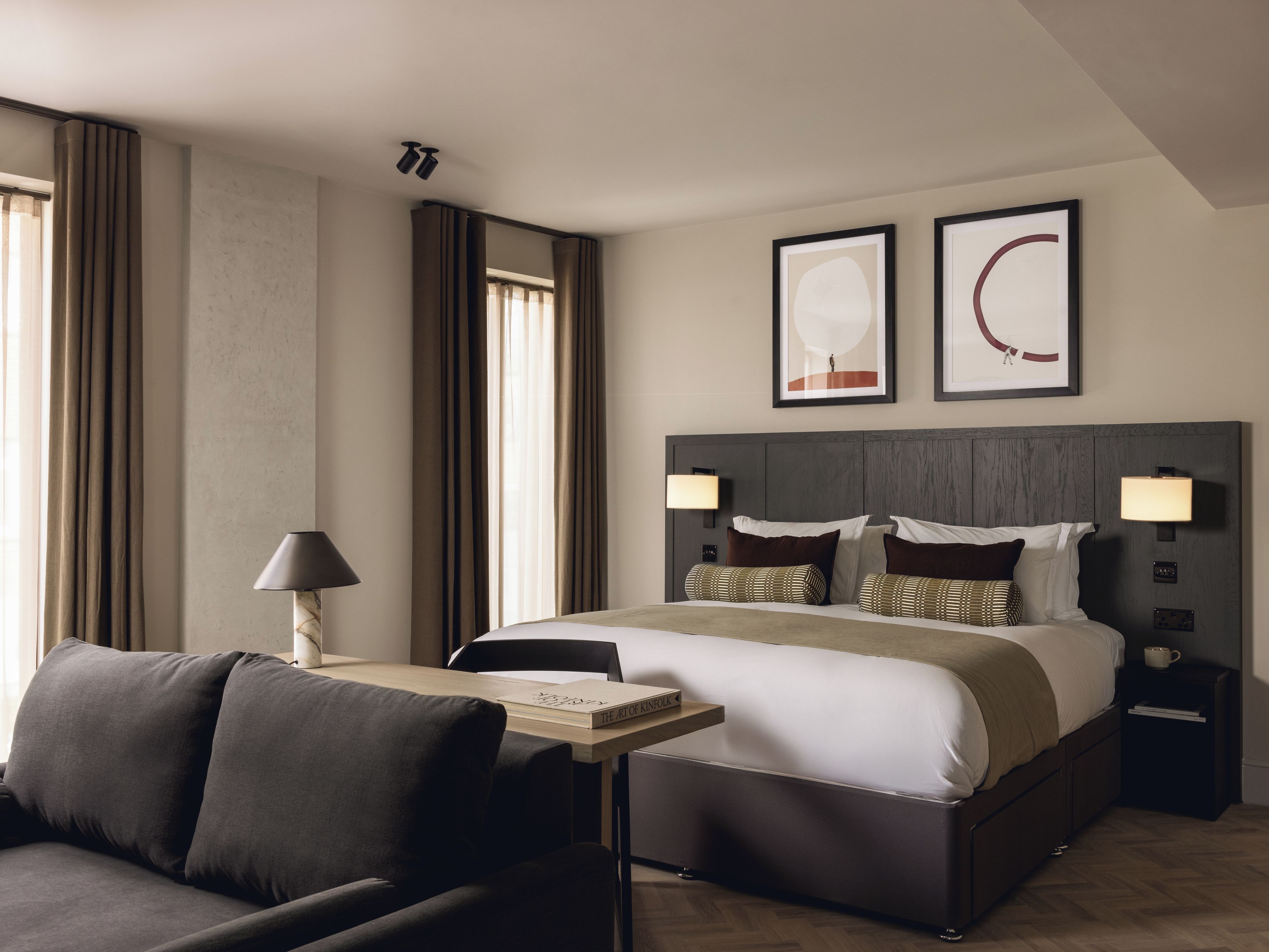Une chambre d’hôtel moderne avec un grand lit, une table de chevet avec une lampe, une chaise et une vue sur la ville.