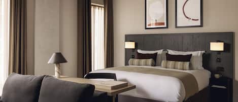 Une chambre d’hôtel moderne avec un grand lit, une table de chevet avec une lampe, une chaise et une vue sur la ville.