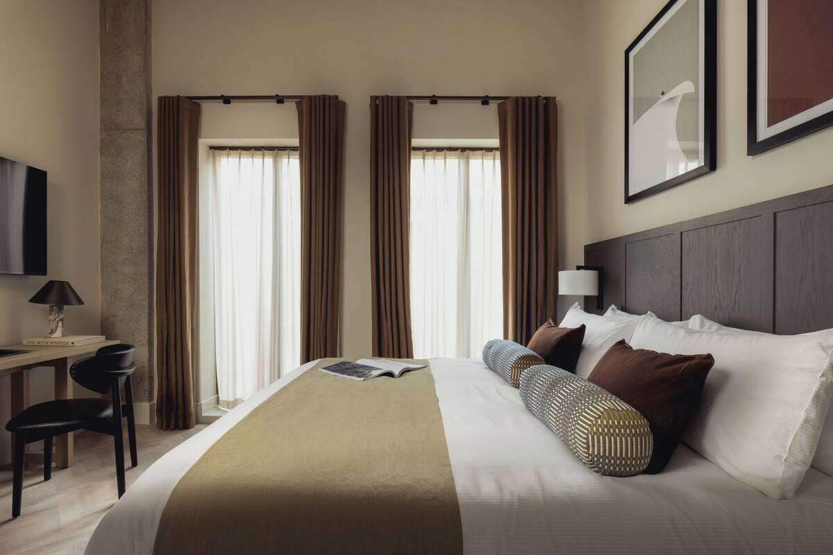 A hotel room with a bed, a desk, a chair, and a television.