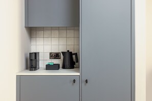 Una kitchenette con cafetera, hervidor y un pequeño electrodoméstico en la encimera.