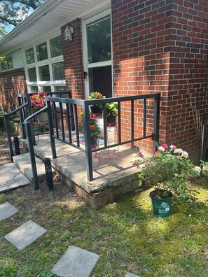 Ein Backsteinhaus mit Veranda, Treppe und Blumentöpfen.