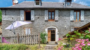 Ein Haus aus Stein mit einer Holztür, einer Satellitenschüssel und einem Holzzaun.
