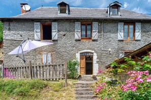 Una casa de piedra con puerta de madera, antena parabólica y cerca de madera.