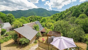 Eine rustikale Holzhütte mit Steinfundament, einer Holzterrasse und einer Pergola mit Dach.