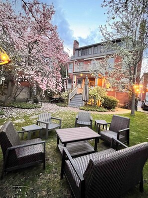 A courtyard with outdoor seating, a staircase leading to a building, and blooming trees. - Steps to Old Port, balcony, private outdoor space (Portland)