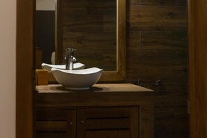 A bathroom with a wooden vanity, a white sink, and a mirror. - Afreeka Beach Hotel (Las Terrenas)