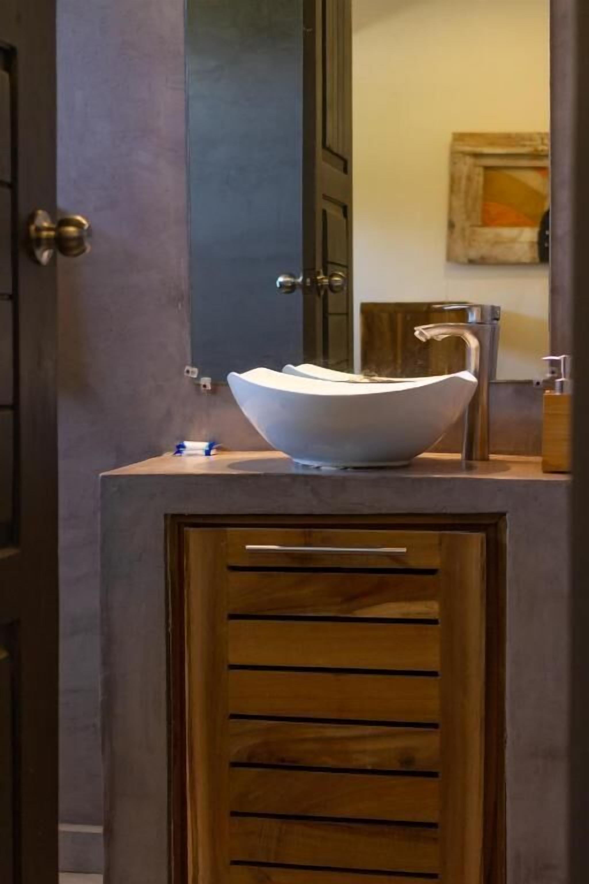 A bathroom with a modern sink, wooden cabinet, and a mirror.