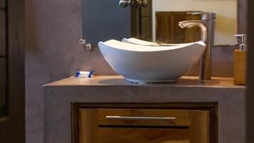 A bathroom with a modern sink, wooden cabinet, and a mirror.