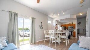 Eine moderne Wohnung mit Essbereich, Küche und einem großen Schiebeglastür nach draußen.