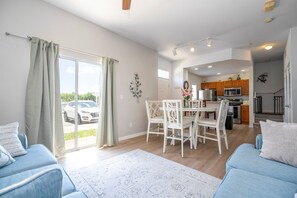 Eine moderne Wohnung mit Essbereich, Küche und einem großen Schiebeglastür nach draußen.