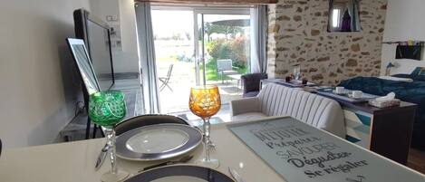 A dining area with a table set for two, a television, and a view of the outdoors.
