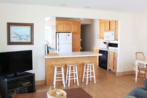 A modern kitchen with wooden cabinets, a white countertop, and a built-in stove. There are two white stools at the kitchen island. - 66n Gorton Avenue, Old Lyme, CT (Old Lyme)