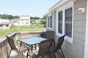 A patio with a table and chairs, a view of the neighborhood, and a house with large windows. - 66n Gorton Avenue, Old Lyme, CT (Old Lyme)