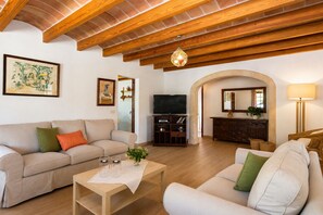 Ein Wohnzimmer mit einer Couch, einem Couchtisch, einem Fernseher, einem Schrank und einer Lampe.