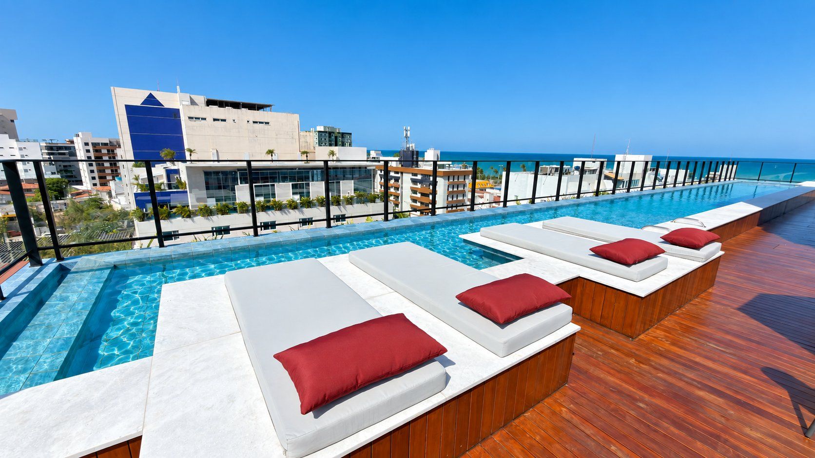 A rooftop pool area with lounge chairs and a view of the ocean.