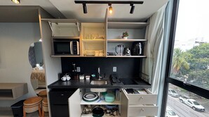 Une cuisine compacte équipée d’un four à micro-ondes, d’une machine à café et de divers ustensiles.
