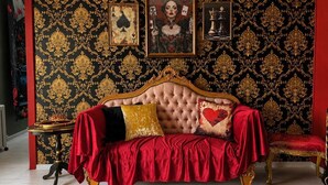 Ein Zimmer mit einem рарillierten Sofa, золотой-rot gemustertem Tapeten und einem Schachspiel an der Wand.