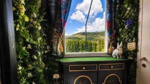 Ein Zimmer mit Fenster, einer gepolsterten grünen Ablage, einem schwarzen Schrank mit goldenen Akzenten und einer weißen Hasenfigur.
