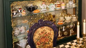 Eine Vitrine mit antiken Tee-Sets und Porzellan-Geschirr, verziert mit aufwendigen Goldakzenten.