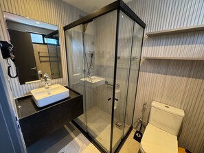 Ein modernes Badezimmer mit einer begehbaren Glasdusche, einem weißen Waschbecken und einer Toilette.