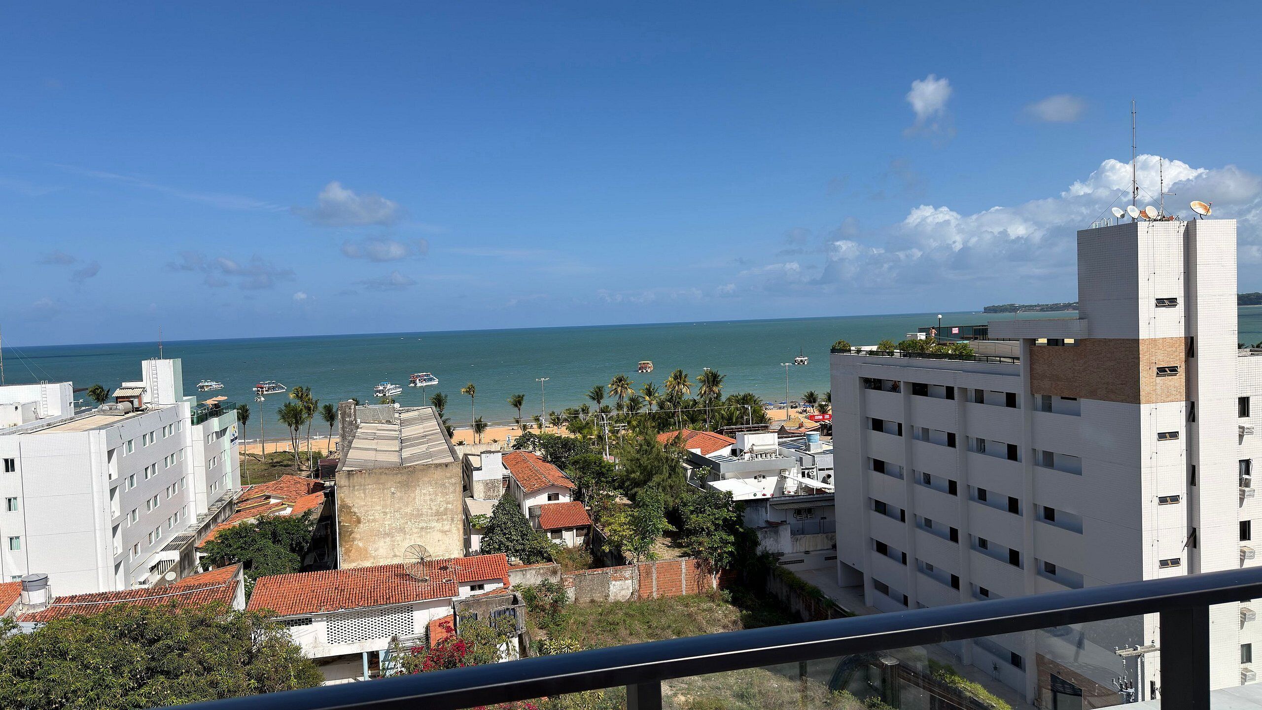Un paisaje costero con vista al mar, edificios con tejados rojos y un edificio alto con antenas parabólicas.