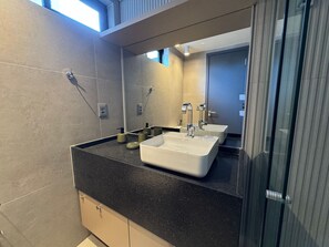 Ein modernes Badezimmer mit zwei Waschbecken, einem Spiegel und einer Duschkabine aus Glas.