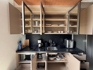 Eine moderne Küche mit offenen Schränken, einer Kaffeemaschine, einem Toaster und einem Spülbecken.