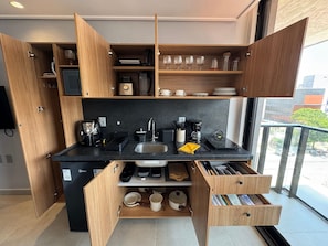 Cocina compacta con electrodomésticos integrados, repisas abiertas y vistas al exterior.