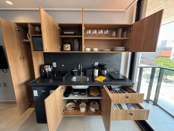 Una cucina compatta con elettrodomestici integrati, ripiani aperti e vista all'esterno.