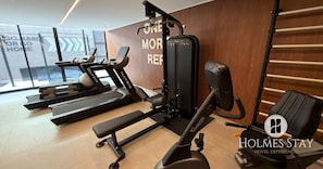 Ein Fitnessraum mit Laufbändern, einer Langhantelbank und einer Wand mit motivierenden Texten.