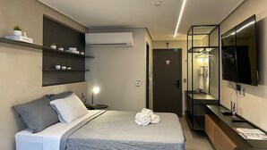 Camera d'albergo moderna con un letto, una lampada da comodino, condizionatore d'aria e uno specchio con televisore.